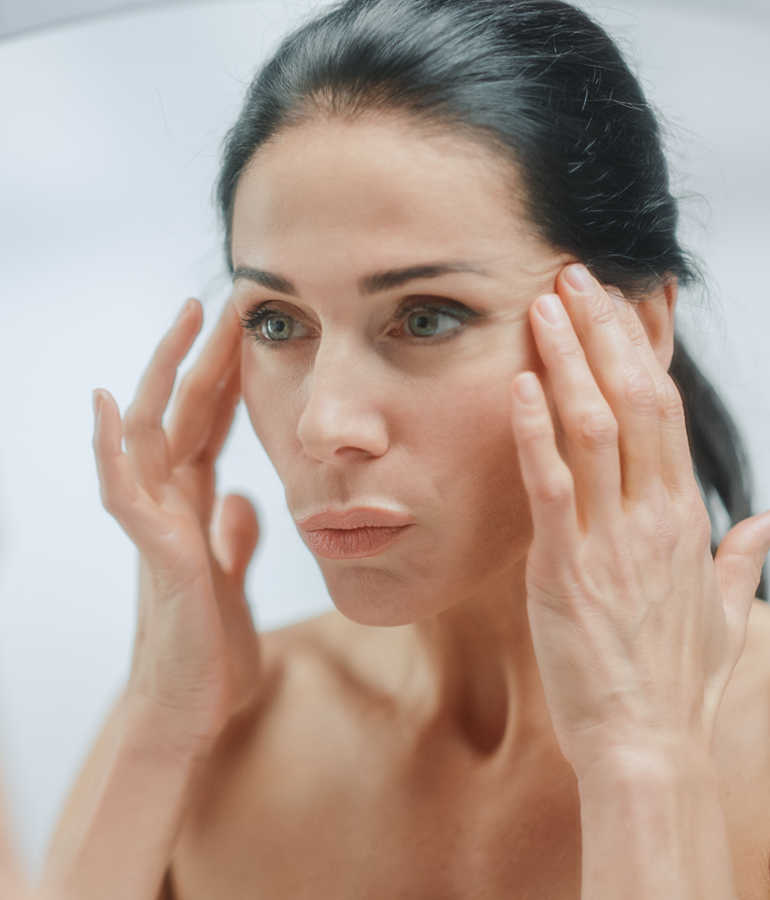 Woman looking in mirror | La Jolla Cosmetic Laser Clinic In San Diego